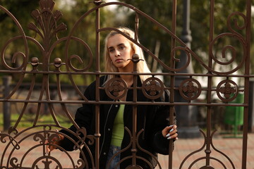 young woman behind a metal fence