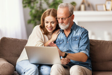 Young woman with father using laptop at home.