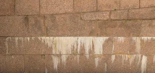 Horizontal picture of old stone wall with white smudges in bright daylight for background or texture