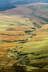 A scenic view of a mountain valley stream with green slopes 