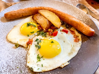 Delicious breakfast with fried eggs, sausage and fried potato slices. Close-up