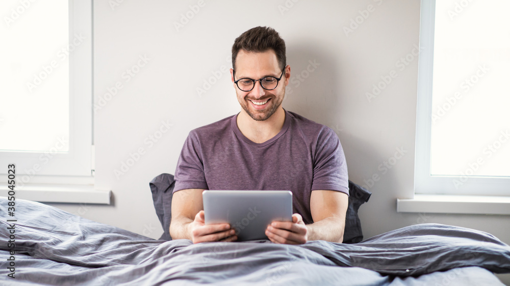 Aufkleber man using digital tablet watching movie online sitting in bedroom
