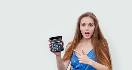 Young white woman is shocked by the number on her calculator. She points her finger at the number.