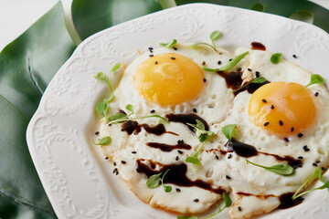 Morning breakfast with fried eggs and plant leaf on white table
