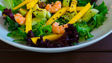 diet salad with shrimp, mango, avocado, cucumber, black sesame seeds and lettuce