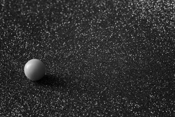 A small smooth ball on a silvery background. An example of asymmetry. Symbolism. Black and white photography. Shallow depth of field.