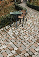 round table and chair on brick path in  autumn park without people
