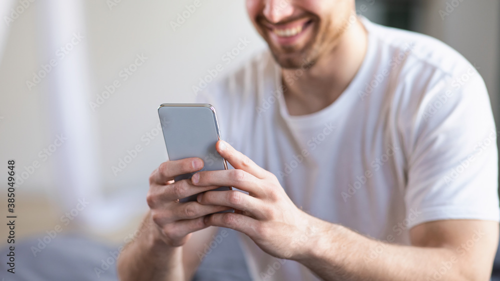 Poster unrecognizable man using smartphone mobile app sitting in bedroom, panorama