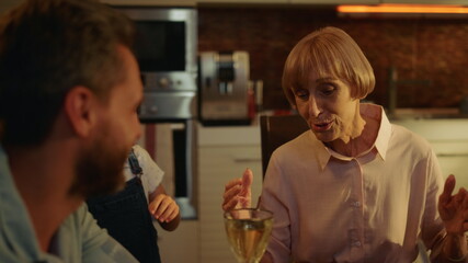 Senior woman talking with adult son at home. Small girl running at kitchen