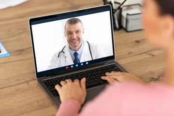 Woman having video call with doctor on laptop at home