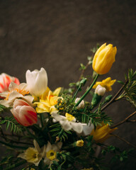 Flower composition on dark background. White, yellow, red flowers. Spring bouquet.