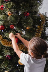 Back view of girl decorating christmas pine at home