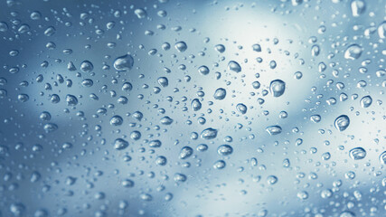 Real water drops on blue gradation background, close up. Raindrops on the window glass. Condensation