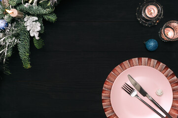 Modern festive table setting for Christmas dinner or New Year eve celebration on rustic wooden black table with copyspace