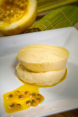 Passion fruit mousse on a white plate with open fruit in the background