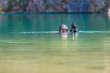 diver in mask plunges into the water, looks into the camera. Head on the surface.