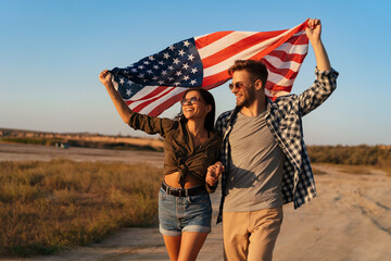 Happy couple holding hands together while strolling with american flag