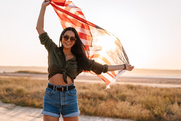 Nice happy girl smiling while strolling with american flag on nature