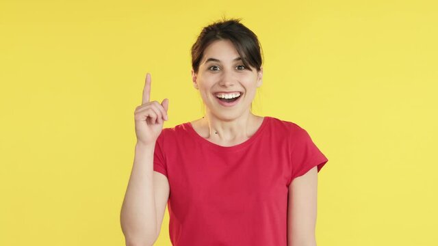 Eureka gesture. Great idea. Happy excited woman in red t-shirt finding decision putting finger up. Looking at camera isolated on yellow copy space. Inspiration news. Brainstorming emotion