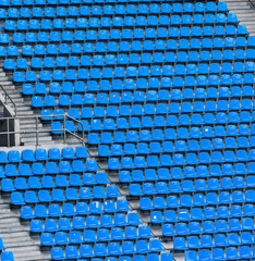 Naklejka premium Many rows of blue seats in a large sports stadium without spectators with concrete stairs.