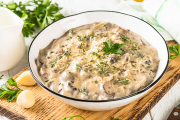 Champignons in cream sauce at white table.