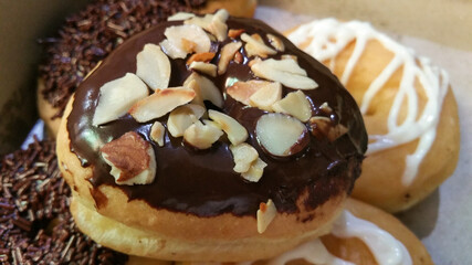 Close-up of homemade chocolate donuts. Donut decorated with delicious chocolate, nuts and almonds with chocolate and sugar garnish full of creativity and delicious texture and taste