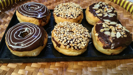 Homemade variation of chocolate donuts on the blackplate. Decorated with delicious chocolate, nuts and almonds with chocolate and sugar garnish full of creativity and delicious texture and taste