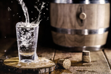 glass overflowing with alcohol, running down the table, drops flying around, splashes. Pure drink,...