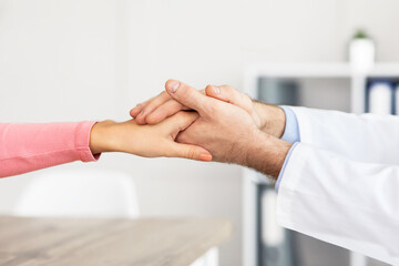 Fototapeta na wymiar Closeup of mature doctor holding female patient's hands