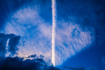 A blue sky in autumn with a line of contrails