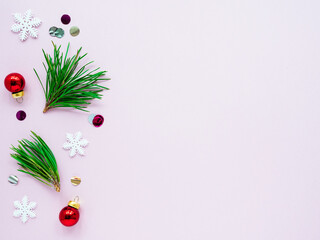 Green Christmas tree branches and decorations on a pink background, top view, copy space, flat lay