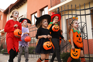 Fototapeta premium Cute little kids wearing Halloween costumes going trick-or-treating outdoors
