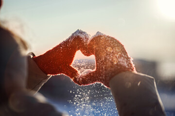 Heart shape symbol of the women's mittens in winter frosty sunset. Concept of frosty winter, dating, valentines day and love.