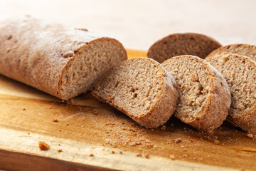 Close-up fresh chopped brown rye bread, slices on wooden cutting board