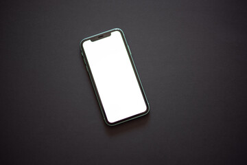 Modern smartphone with the turned on white screen on the dark (black) background. Modern and minimalistic concept.