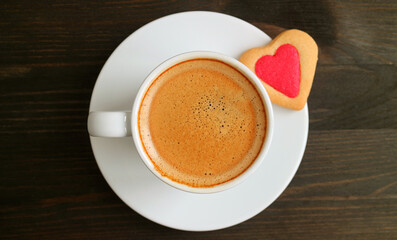 Top View of a Cup of Hot Coffee with Heart Shaped Cookie on Dark Brown Wooden Table for the Concept of LOVE
