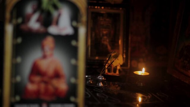 Altar with incense, deities and oil lamp lit. Static, shallow focus