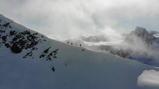 A group of three ski-mountaineers walking on the edge of a snowed mountain in the Pyrenees.