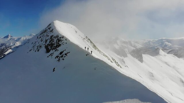 A group of three ski-mountaineers walking on the edge of a snowed mountain in the Pyrenees.