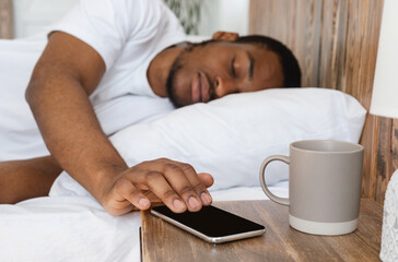 African Man Sleeping Through Alarm-Clock On Phone Lying In Bedroom