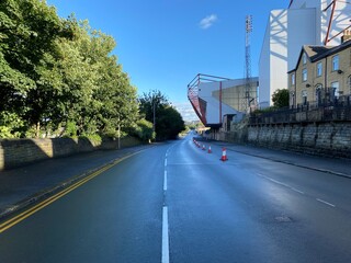 Looking down Midland Road, after a heavy rain shower, with old trees, houses, and football ground in, Bradford, Yorkshire, UK