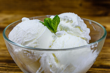 Glass bowl with ice cream balls and mint leaf on a wooden table