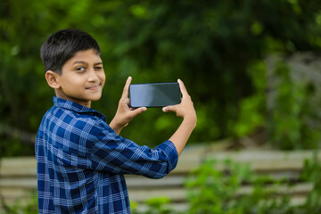 Cute indian little child showing smartphone with blank screen