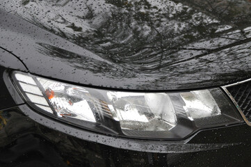 Detail of car headlights lamp, black modern car front lamp and raindrops