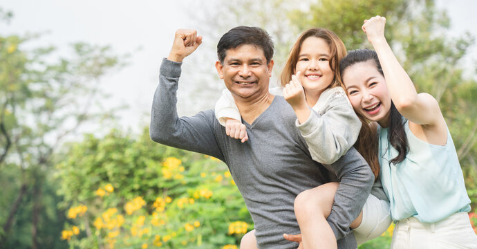 Asian Family Is Stand The Park, Which Is Ideal For Long Weekend Vacations. Taking Care Of Family Makes Children Feel The Love Of Parenting. Family Health Insurance Is A Good Plan.