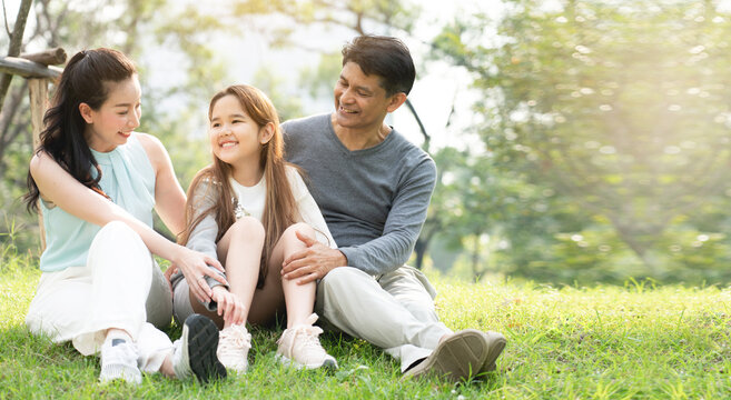 Asian Family Is Sitting And Chatting The Park, Which Is Ideal For Long Weekend Vacations. Taking Care Of Family Makes Children Feel The Love Of Parenting. Family Health Insurance Is A Good Plan.