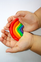 The kid sculpts a rainbow. Rainbow in a child's hand. hands holding colorful beads. Rainbow in a child's hand.