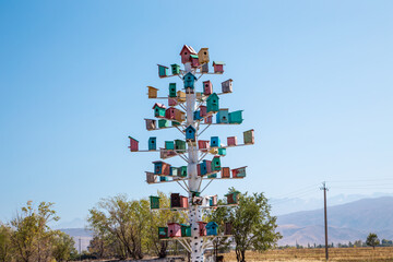 Birdhouse, bird house. Many wooden multi-colored houses on a decorative tree. Against the background of the blue sky. copy space. Kyrgyzstan.