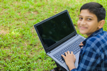Technology concept : Cute indian little school boy using laptop