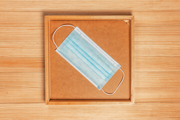 Medical protective surgical mask in a picture frame close-up on a wooden surface.